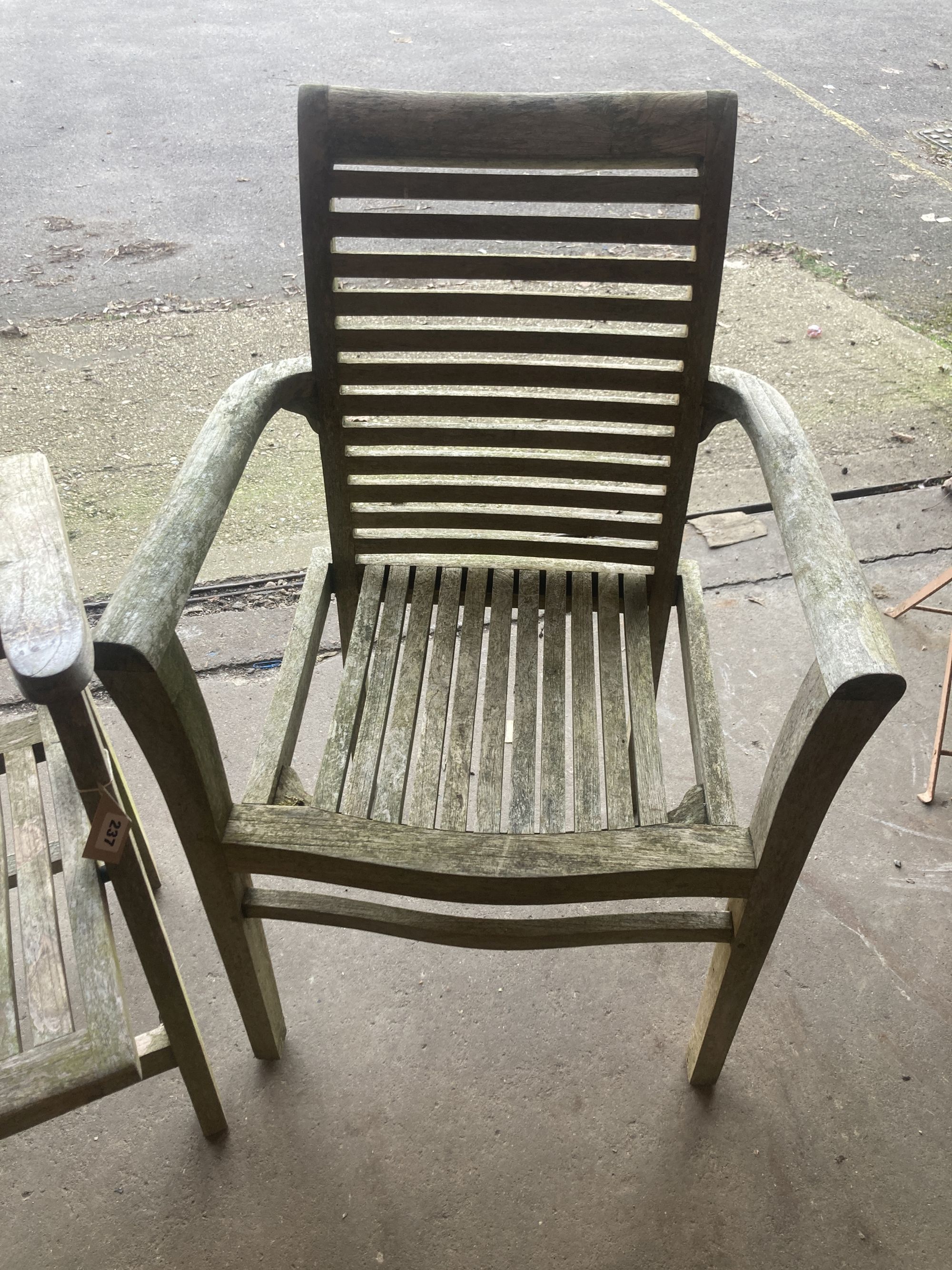 A weathered teak folding garden armchair, together with a teak garden elbow chair
